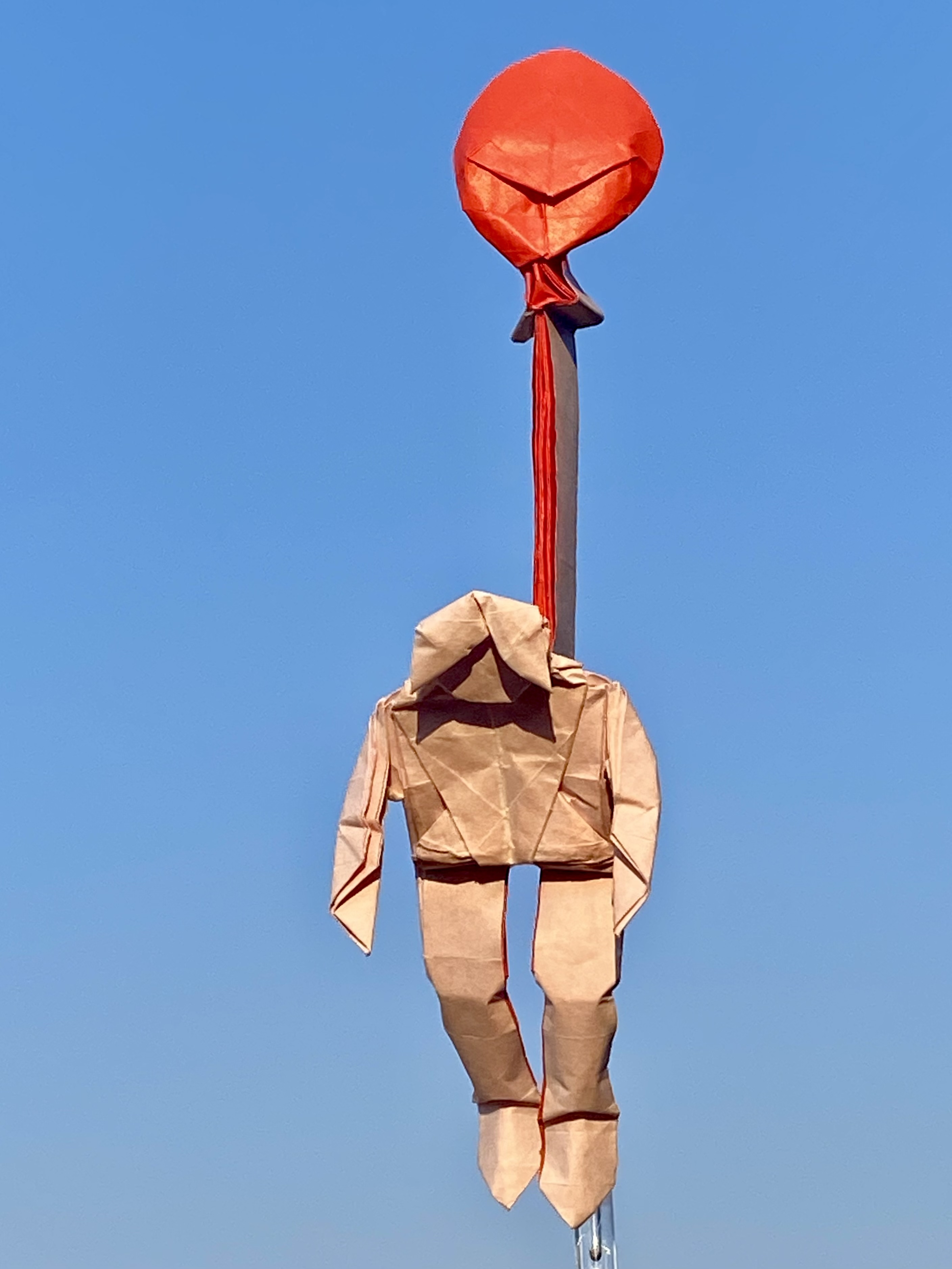 Origami person hanging by balloon.